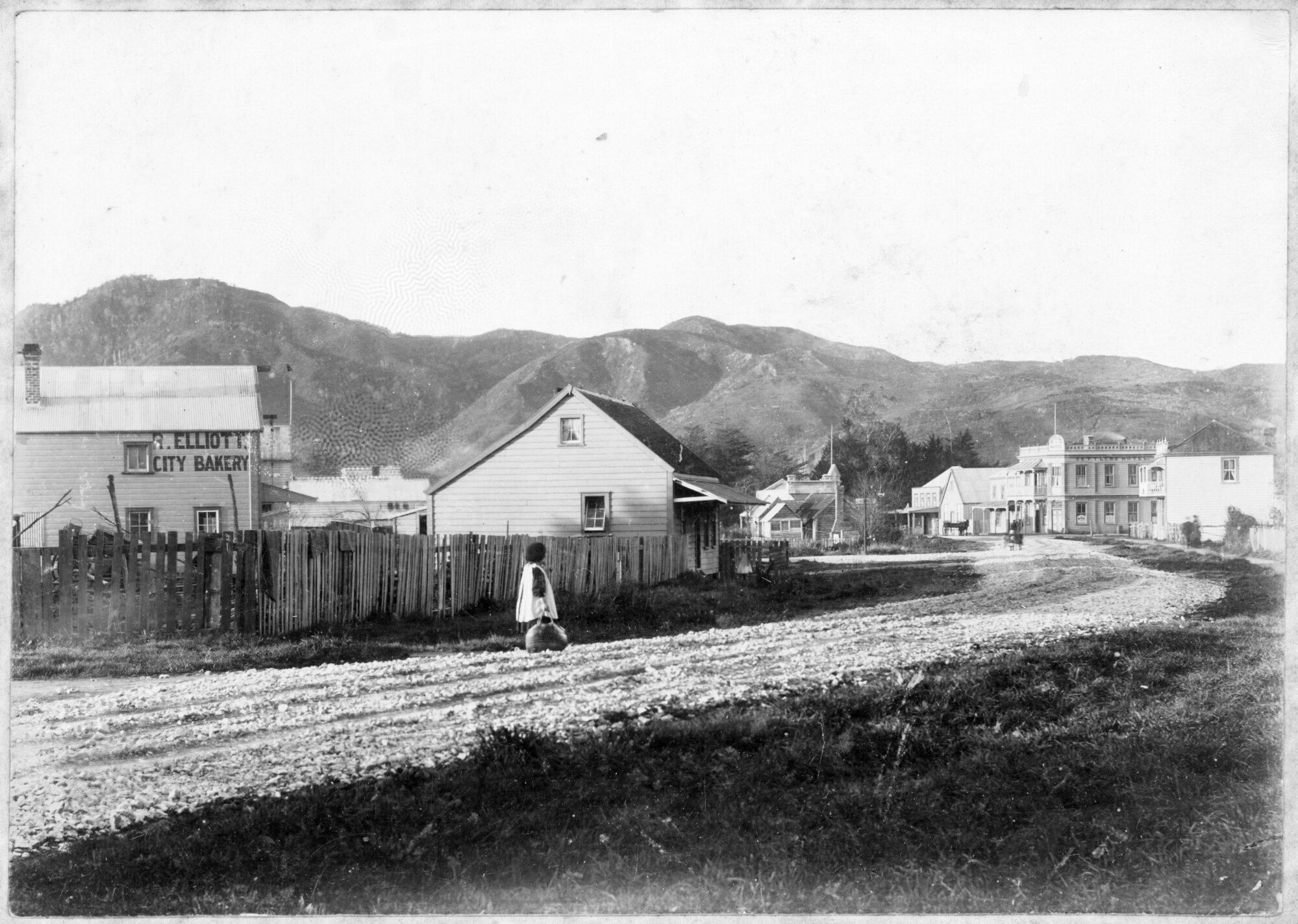 Road next to R. Elliott City Bakery and house looking toward Settlers Hotel